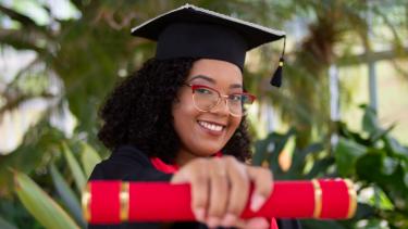 young women in grad apparel holding a diploma
